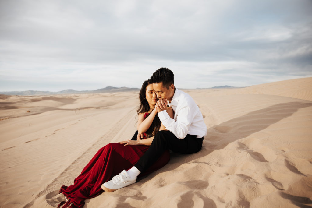 sand dunes engagement photos man kisses hand of woman