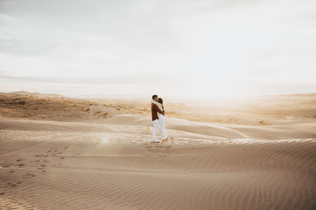 couple embrace in the sand dunes utah