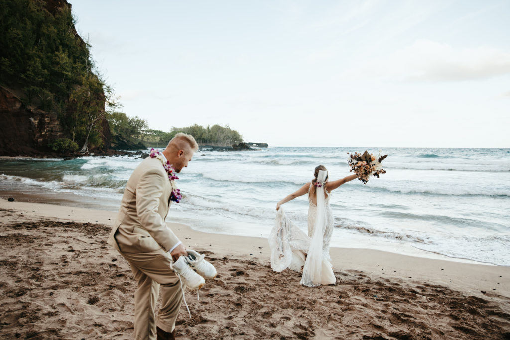 bride and groom jump into the ocean after eloping in maui