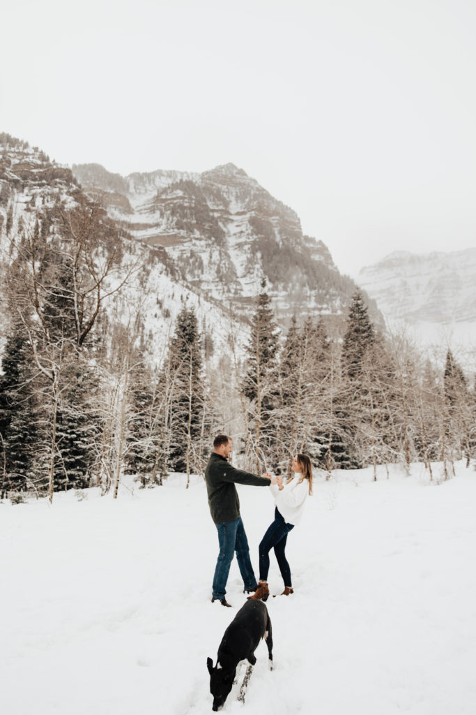 couple playing in the snow with their dog in utah
