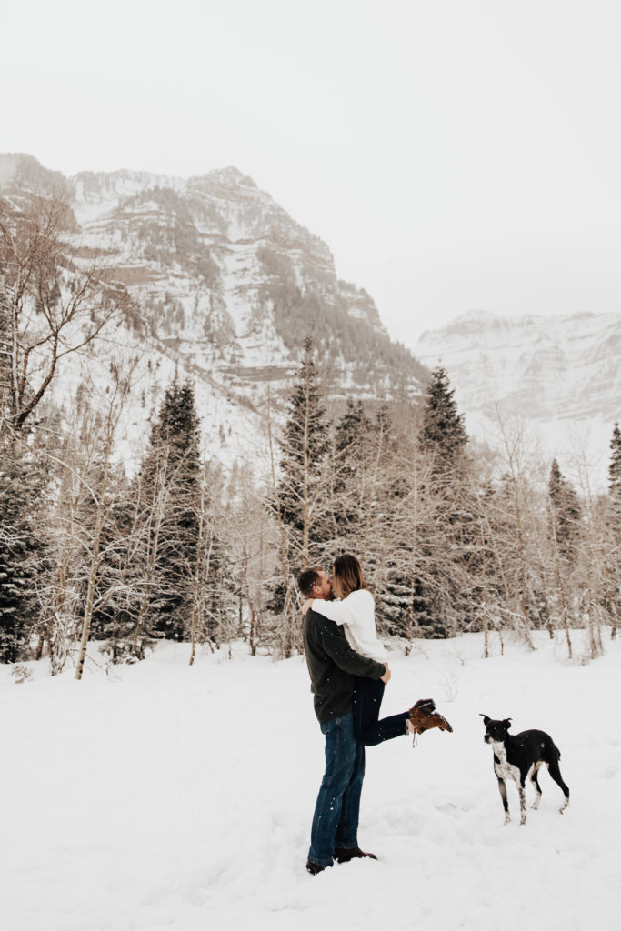man holding woman in snowy engagement photos