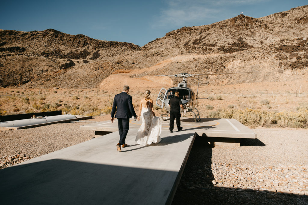 bride and groom walking towards helicopter