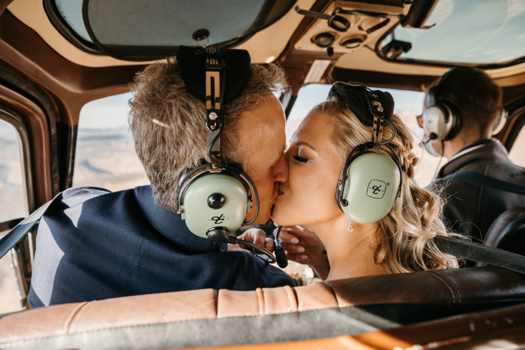 bride and groom kiss in helicopter ride with noice canceling headphones on